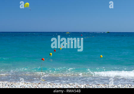 Tourists have fun parasailing in the azure Mediterranean sea at a great distance from the coast near Rhodes (Greece) Stock Photo