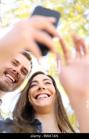 Happy couple using smart phone together laughing watching online content in a park Stock Photo