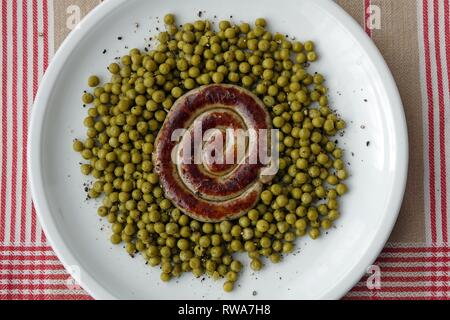 Bratwurst snail with peas on a plate, Germany Stock Photo