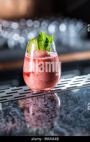 Cocktail drink frozen strawberry daiquiri at barcounter in night club or restaurant. Stock Photo