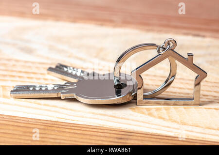 keys and keychains in the shape of a house on a wooden background Stock Photo