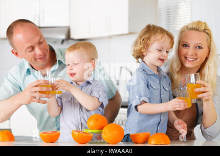 Happy family is preparing Orange Juice at kitchen. Stock Photo