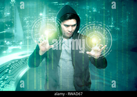Young asian hacker in black hoodie touching virtual screen with binary code over digital background Stock Photo