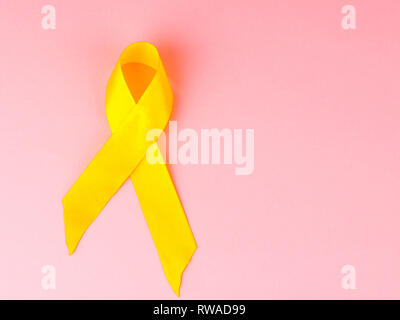 Childhood Cancer Awareness Yellow Ribbon on pink background. Childhood Cancer Day. Stock Photo