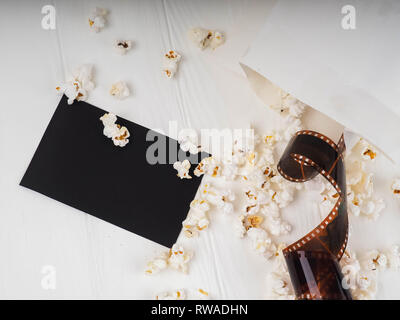 photographic film strip on white wooden background, popcorn. Stock Photo