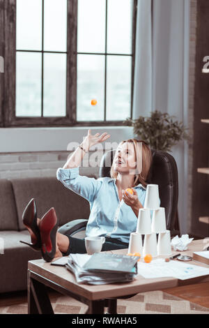 Woman going crazy at work playing with tennis ball Stock Photo