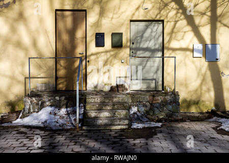 Old yellow wall with tree shadow, two doors and steps. Architecture and nature background Stock Photo