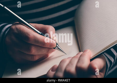Close up of woman's hand writing in notebook, selective focus with natural light Stock Photo