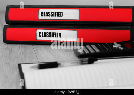 Red folders with classified written on the label on a desk with selective colour Stock Photo