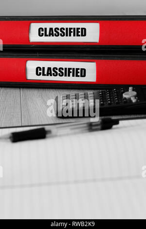 Red folders with classified written on the label on a desk with selective colour Stock Photo