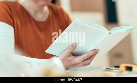 Female carpenter reading DIY project instruction manual in small business woodwork workshop Stock Photo