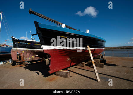 Two traditional wooden fishing boats out of the water on the harbour front at Anstruther Fife Scotland UK Stock Photo