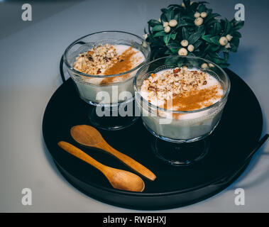 Rice pudding served in glass cups. Decorated. Close-up.Homemade dessert decorated with flower on black tray. Stock Photo