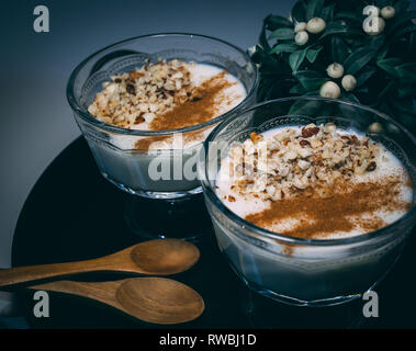 Rice pudding served in glass cups. Decorated. Close-up.Homemade dessert decorated with flower on black tray. Stock Photo