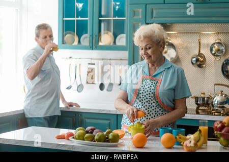 Granny squeezing an orange half Stock Photo