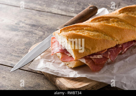 Spanish serrano ham sandwich on wooden table. Stock Photo
