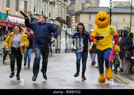 Chippenham, Wiltshire, UK. 5th March, 2019. Heavy rain this afternoon failed to dampen the spirits of local people taking part in the annual pancake race on Chippenham high street.  Credit: Lynchpics/Alamy Live News Stock Photo