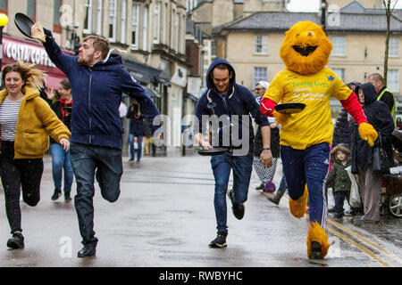 Chippenham, Wiltshire, UK. 5th March, 2019. Heavy rain this afternoon failed to dampen the spirits of local people taking part in the annual pancake race on Chippenham high street.  Credit: Lynchpics/Alamy Live News Stock Photo