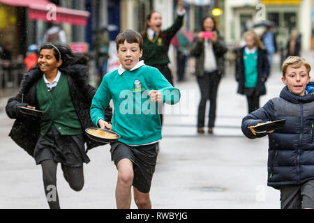 Chippenham, Wiltshire, UK. 5th March, 2019. Heavy rain this afternoon failed to dampen the spirits of local children who are pictured taking part in the annual pancake race on Chippenham high street.  Credit: Lynchpics/Alamy Live News Stock Photo