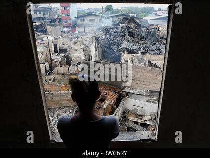 Quezon City, Philippines. 6th Mar, 2019. A resident looks at charred homes after a fire at a residential area in Quezon City, the Philippines, March 6, 2019. Around 150 houses were razed in the fire, leaving 450 families homeless. Credit: Rouelle Umali/Xinhua/Alamy Live News Stock Photo