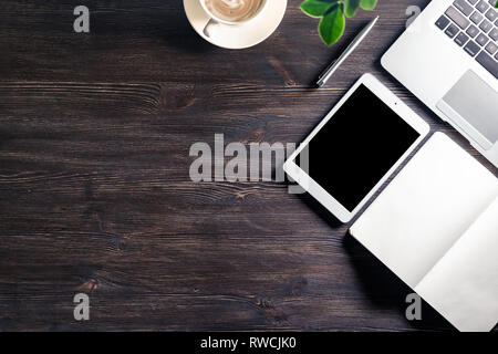 Business work desk with laptop and digital tablet notebook pen watch on dark wooden table, modern workplace tabletop background with devices and coffe Stock Photo