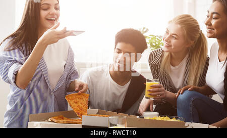 Young blogger taking photo of pizza, having party with friends