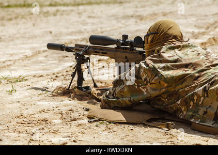 Young male sniper in camouflage with gun in the desert. Stock Photo