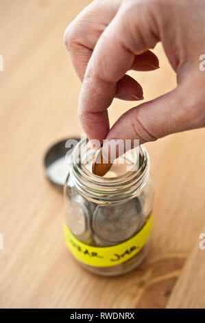 hand putting a coin into a swear jar Stock Photo