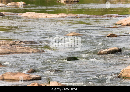 abstract or background of a long exposure of water flowing or cascading and tumbling over rocks and stones and small or gentle rapids in a river Stock Photo