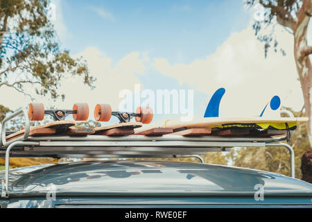 Skateboards and surfboard tied up on top of roof rack of vintage car Stock Photo