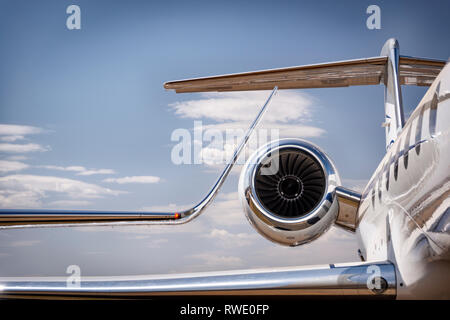 A winglet and engine of a luxury personal jet aircraft against a blue sky with cloud Stock Photo