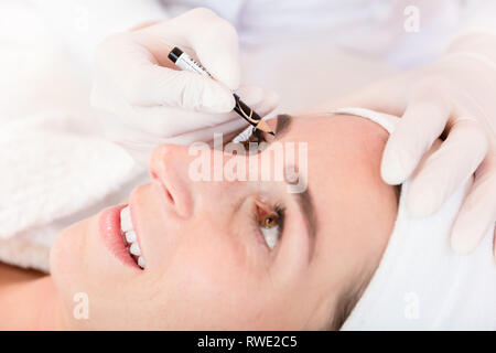 Make up artist working on woman's eyebrows in salon Stock Photo