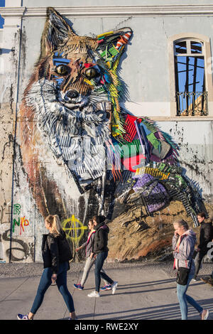 Lisbon, Portugal, February 02, 2018 - People walking in front of big fox sculpture made of plastic trash on the wall of abandoned building by portugue Stock Photo