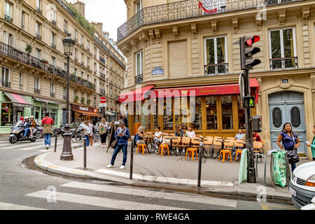 A woman looks at her mobile phone standing outside Le Ventura restaurant cafe on Rue des Martyrs in Monmartre in the 9th arrondissement of Paris Stock Photo