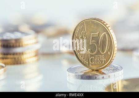 Euro coin balances on another coin and several loose coins Stock Photo