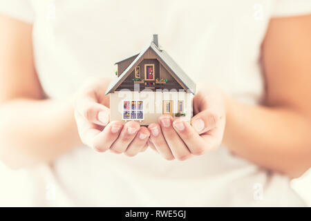 Hands of young woman holding model house Stock Photo