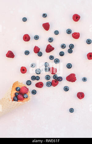 Creative Summer concept composition flat lay top view sweet fresh red raspberries blueberries ice cream waffle cone pink background copy space Templat Stock Photo