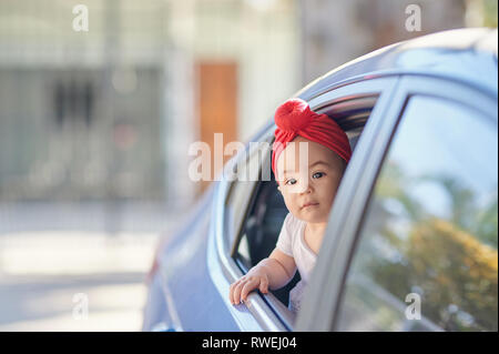 Summer trip theme. Little girl in red hat travel on car Stock Photo