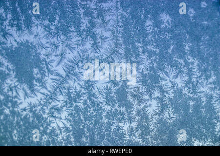 A frozen window with unique ice patterns formed Stock Photo