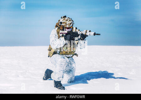 Army soldier shooting in kneeling position in the Arctic. Stock Photo