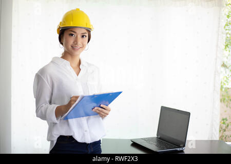 Asian women engineering inspecting and working and holding blueprints at office Stock Photo