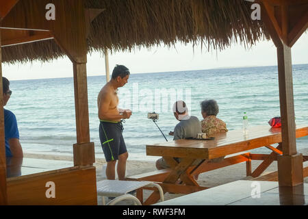 Elderly Tourist Couple Taking Photos With Selfie Stick - Panglao Beach, Bohol - Philippines Stock Photo