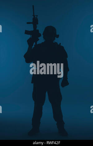 Silhouette of a U.S. Marine Corps Marsoc raider with weapon, blue background. Stock Photo