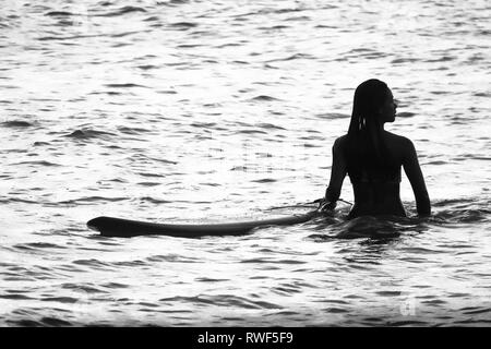 Island Surfer Girl waiting in Water With Surfboard, Cloud 9 - Siargao, Philippines Stock Photo