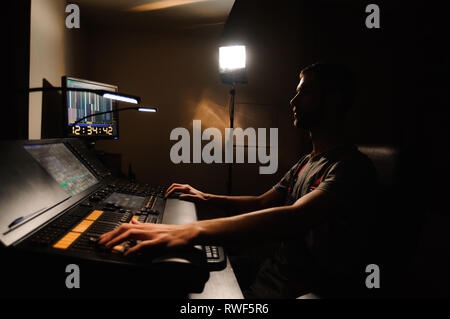 A lighting engineer works with lights technicians control on the concert show. Professional light mixer, mixing console. Equipment for concerts. Stock Photo