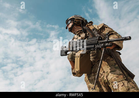 Low angle portrait of U.S. Army Ranger with machine gun, looking up to sky. Stock Photo