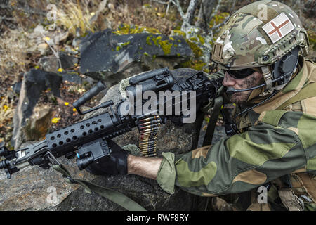 Norwegian rapid reaction special forces FSK soldier firing among the rocks. Stock Photo