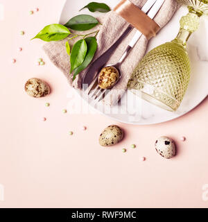 Easter natural table setting decorated with quail eggs and green sprigs. Beautiful arrangement. Stock Photo