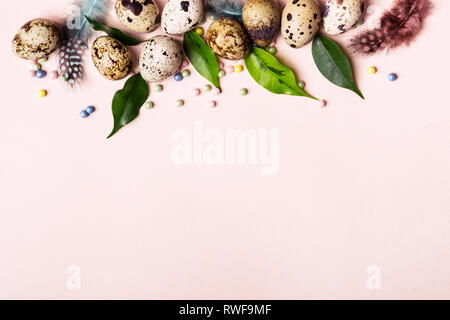 Easter nature border of quail eggs, green leaves and feathers. Stock Photo