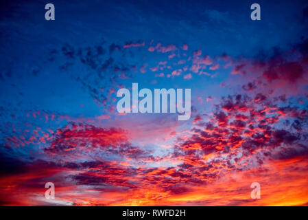 The magnificent deep blue color of the sky and golden yellow and orange of the clouds after sunset. Stock Photo